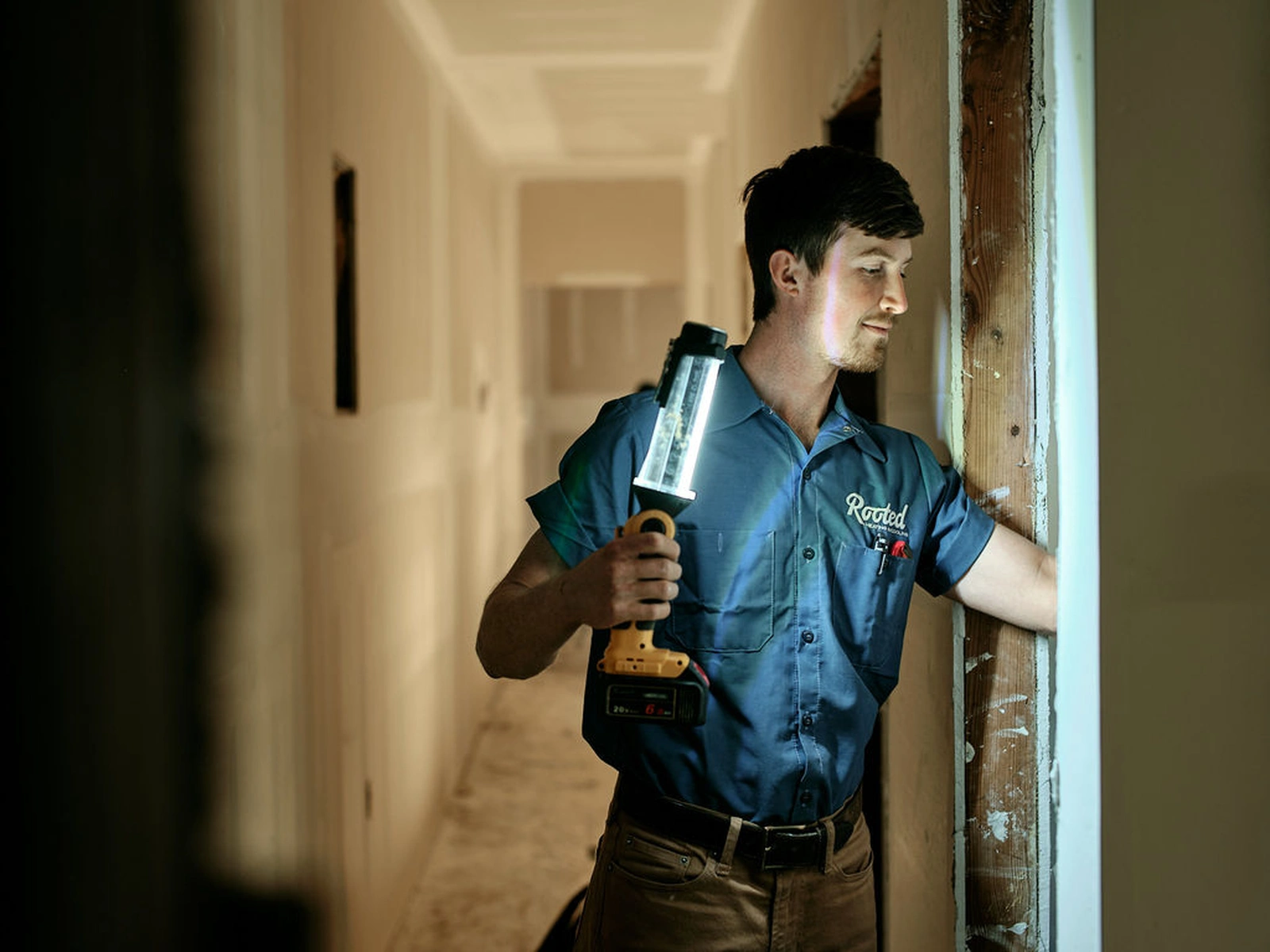 AC repair service technician working with a hand lamp in a hallway