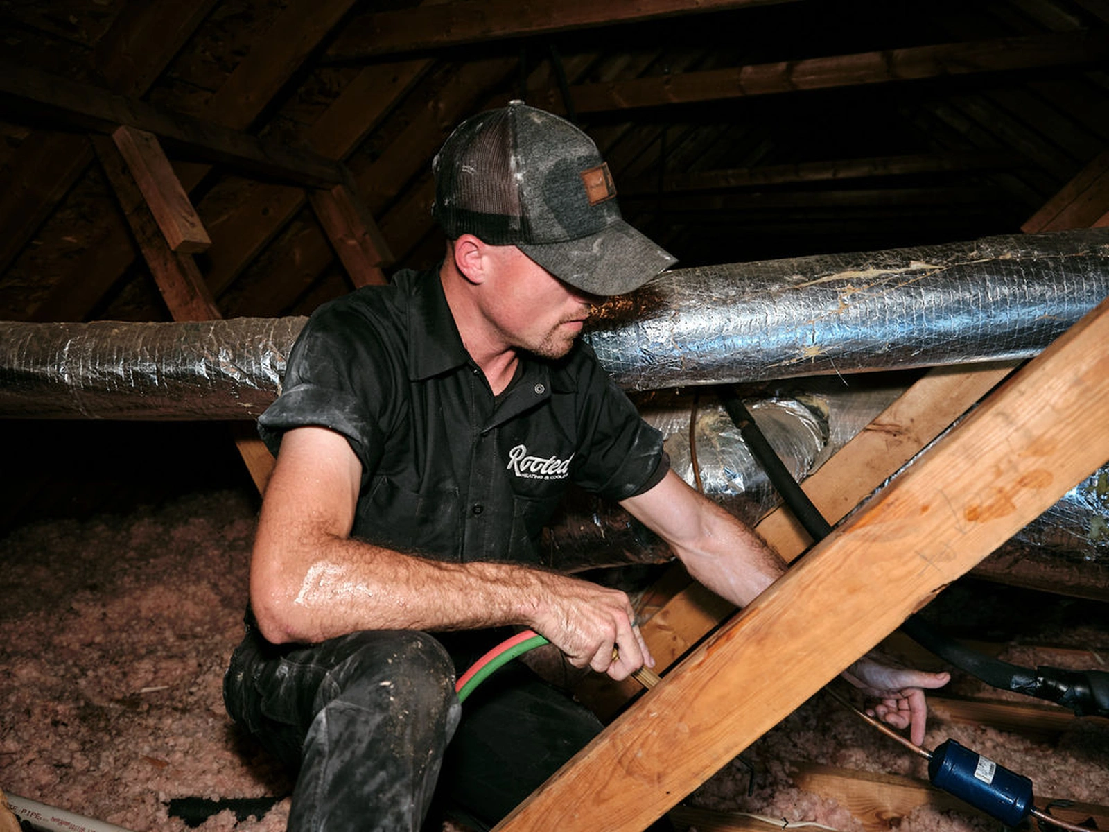 HVAC contractor installing ductwork and pipes in a Jackson-area attic