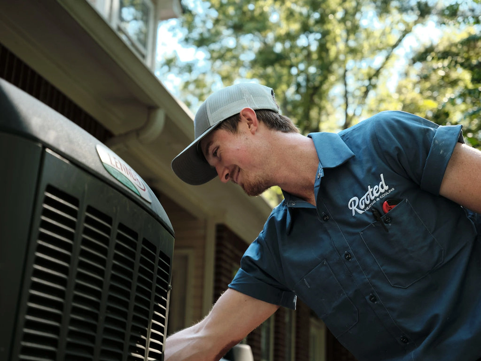 Rooted Heating & Air technician repairing an outdoor AC unit