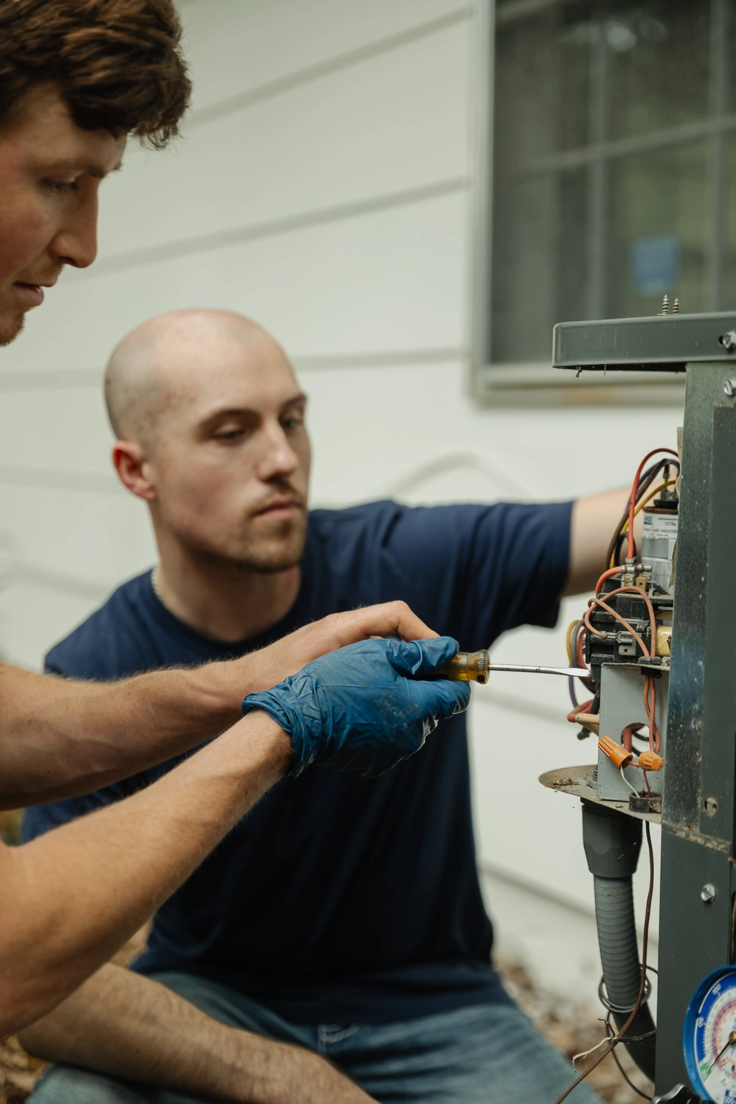 Rooted Heating & Air technicians repairing an outdoor condenser disconnect