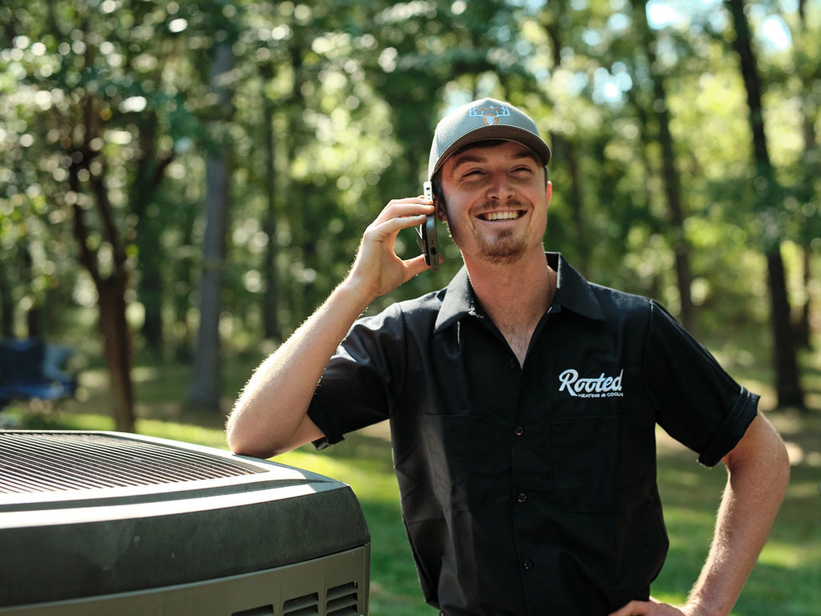 Logan, Rooted Heating & Air HVAC technician, on the phone outdoors