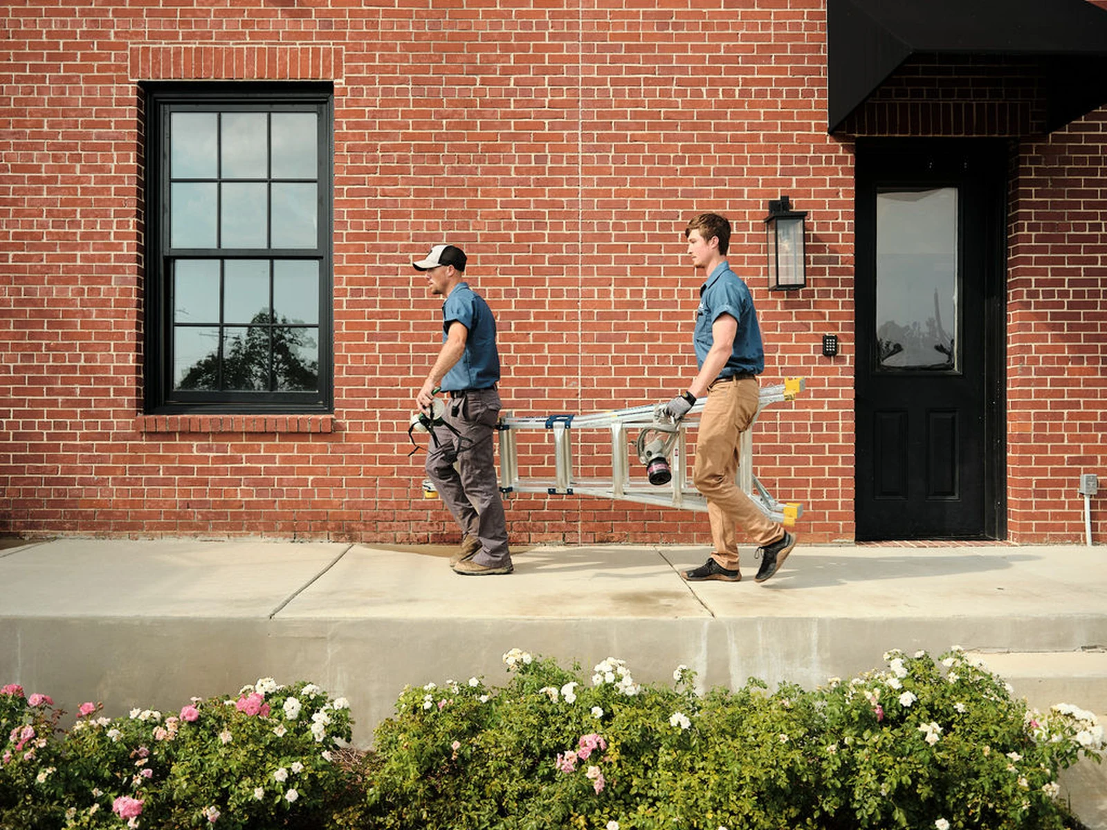Two workers carrying ladder for AC repair service
